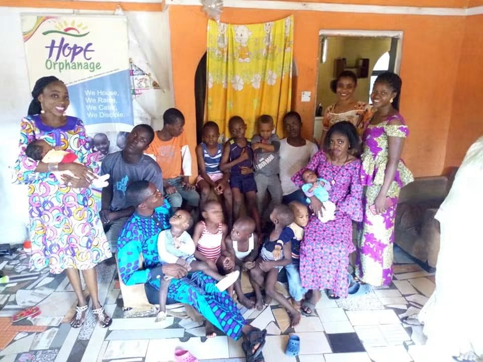 Volunteers seated with children in a bright orange room